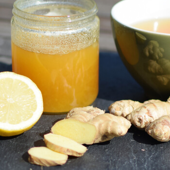 KI generiert: Das Bild zeigt eine Tasse mit frisch gebrühtem Tee und einem Teesieb. Daneben liegt ein Jutebeutel mit der Aufschrift "Tea" und lose Teeblätter.