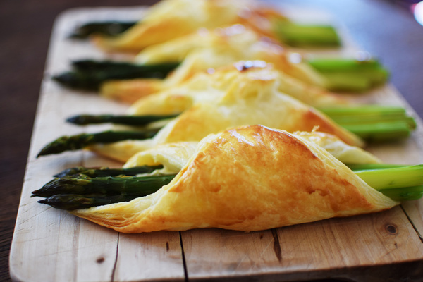 KI generiert: Gebackener Spargel im Blätterteig auf einem Holzbrett.