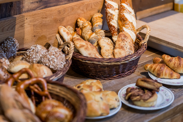 KI generiert: Verschiedene Brote und Gebäck in Körben und Tellern in einer Bäckerei.