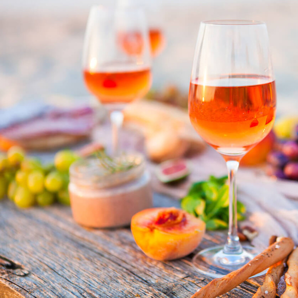 KI generiert: Weingläser, Früchte und Snacks auf einem Tisch, Hintergrund unscharf.