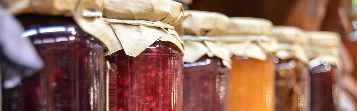 KI generiert: Eine Reihe von Glasbehältern mit verschiedenen Konfitüren und Papierabdeckungen.