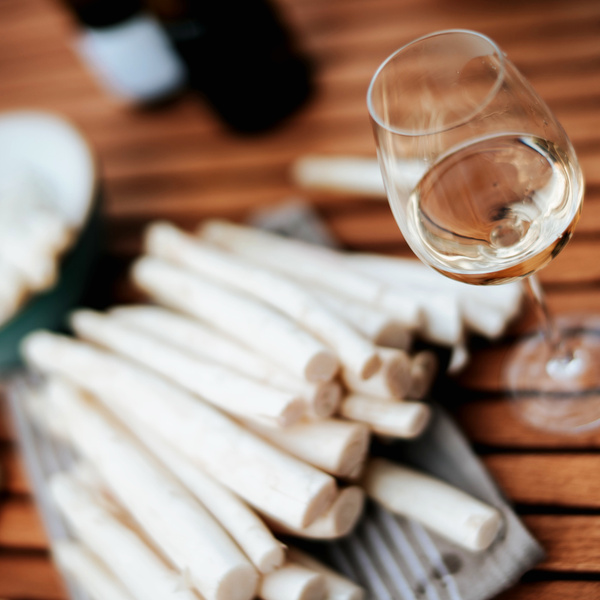 KI generiert: Weißwein und Spargel auf einem Holztisch arrangiert.