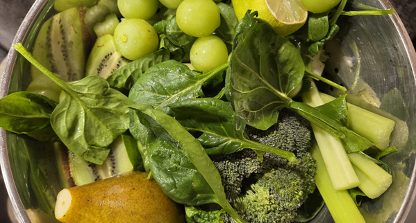 KI generiert: Eine Schüssel mit grünem Obst und Gemüse: Spinat, Weintrauben, Kiwi, Brokkoli, Birne, Sellerie und Limette.