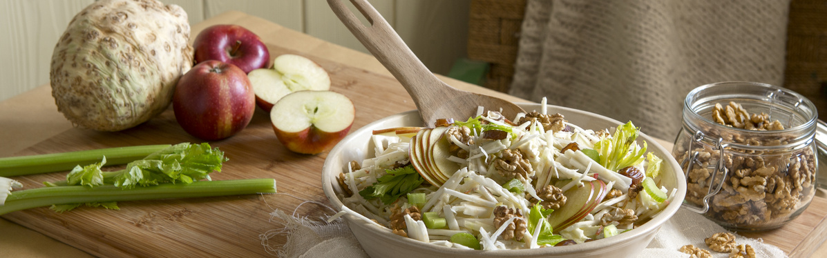 KI generiert: Ein Teller Walnuss-Salat mit Sellerie, Äpfeln und einem Glas Walnüsse.