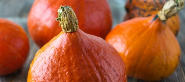 KI generiert: Hokkaido-Kürbisse in Nahaufnahme auf einem Holztisch.