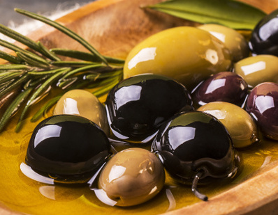 KI generiert: Verschiedene Oliven und ein Rosmarinzweig auf einem Holzlöffel.