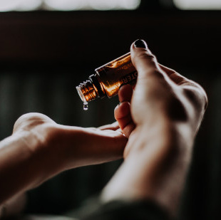 KI generiert: Eine Person tropft Öl aus einer kleinen Flasche in ihre Hand.