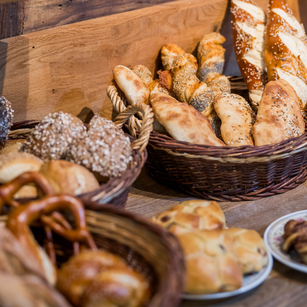 KI generiert: Verschiedene Brotsorten und Brötchen in Körben auf einem Tisch.