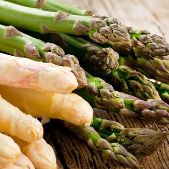KI generiert: Frischer Spargel, sowohl weiß als auch grün, auf einem Holztisch.