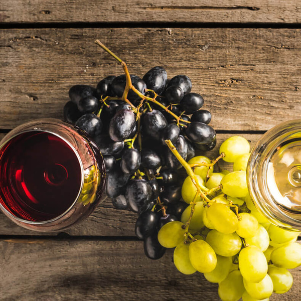 KI generiert: Trauben mit Rot- und Weißweingläsern auf einem Holztisch.