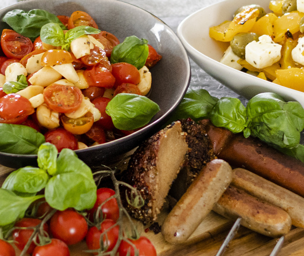 KI generiert: Vielseitige, bunte vegetarische Platte mit Tomatensalat, gelber Paprika, Wurst und frischen Kräutern.