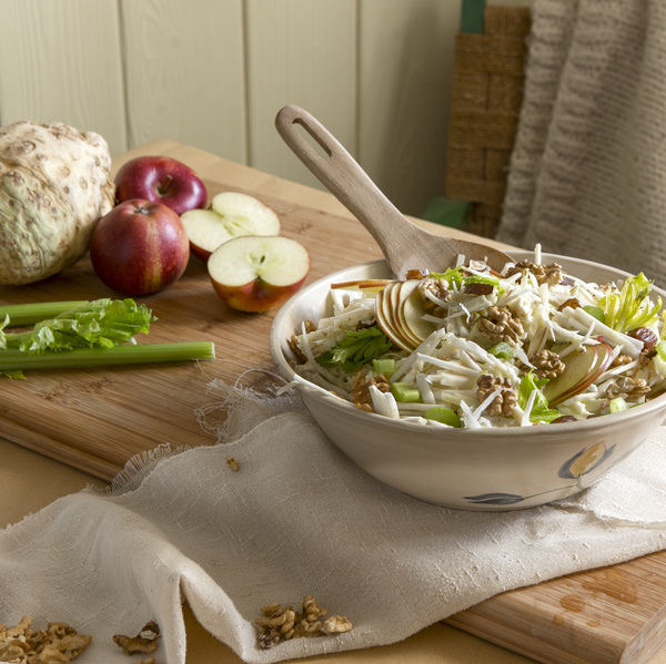 KI generiert: Ein frischer Salat mit Sellerie, Äpfeln und Walnüssen in einer Schüssel auf einem rustikalen Tisch.