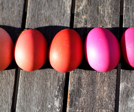 KI generiert: Farbige Eier auf einem Holztisch in der Sonne.