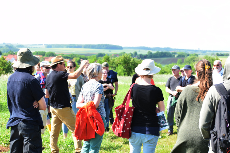KI generiert: Eine Gruppe von Menschen steht auf einem Feld, wahrscheinlich bei einer Führung oder einem Workshop.