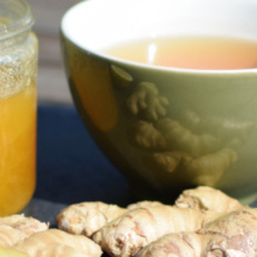 KI generiert: Das Bild zeigt eine Tasse mit frisch gebrühtem Tee und einem Teesieb. Daneben liegt ein Jutebeutel mit der Aufschrift "Tea" und lose Teeblätter.