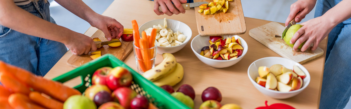 KI generiert: Personen schneiden Obst und Gemüse auf einem Tisch in der Küche.