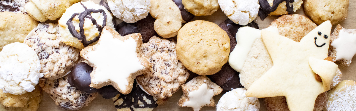 KI generiert: Auf dem Bild sind verschiedene Sorten von Keksen auf einem Tisch arrangiert. Die Kekse haben unterschiedliche Formen und Designs, von einfachen Plätzchen bis hin zu dekorierten Sternen.