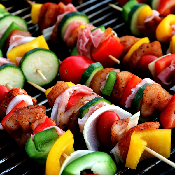 KI generiert: Bunte Gemüse- und Fleisch-Spieße auf einem Grill.