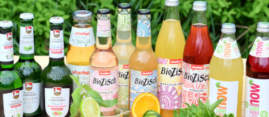KI generiert: Verschiedene bunte Flaschen mit Bio-Getränken vor grünem Hintergrund. Markenname: Voelkel BioZisch.
