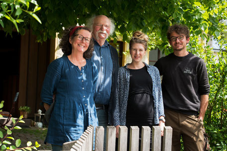 2 lächelnde Frauen stehen in Schürze vor ihrem Hofladen, die eine hält einen runden Käselaib in der Hand