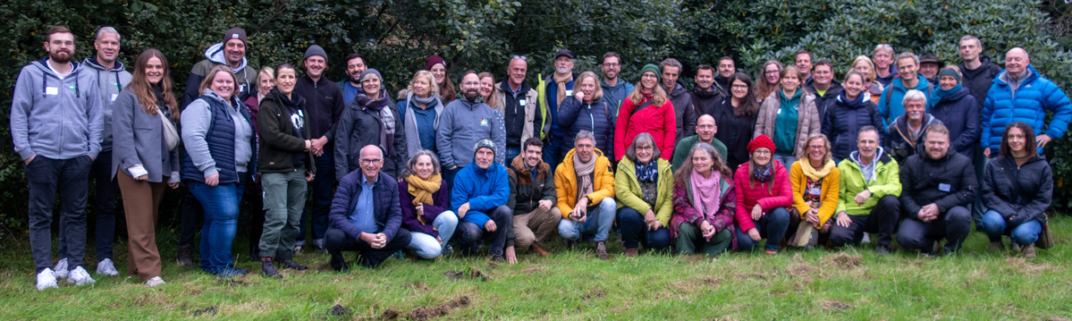 KI generiert: Eine Gruppe von Menschen posiert draußen auf einer Wiese für ein Gruppenfoto.
