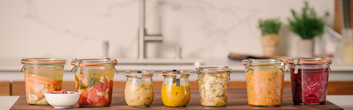 KI generiert: Verschiedene Einmachgläser mit eingelegtem Gemüse stehen auf einer Küchenarbeitsplatte.