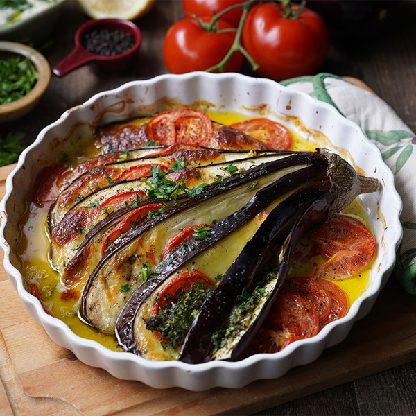 KI generiert: Ein Auflauf mit Auberginen und Tomaten in einer weißen Form, dekoriert mit Kräutern.