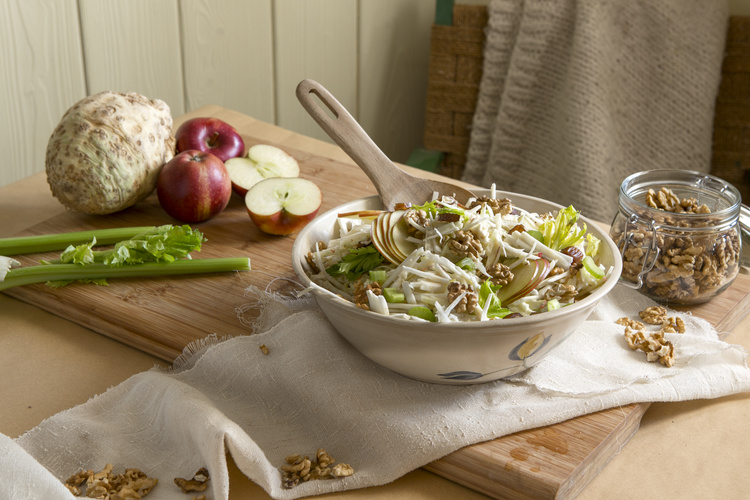 KI generiert: Eine Schüssel mit frischem Waldorfsalat aus Äpfeln, Sellerie und Walnüssen auf einem Tisch.
