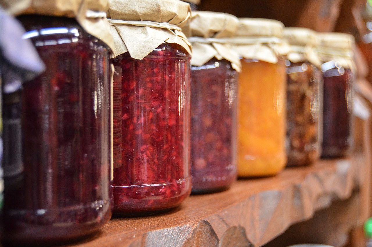 KI generiert: Verschiedene Gläser mit Marmeladen und Chutneys auf einem Holzregal.