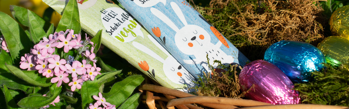 KI generiert: Ein Osterkorb mit Schokolade, Blumen und bunten Eiern. Text: "Ei Ei Ei! Schokolade vegan."