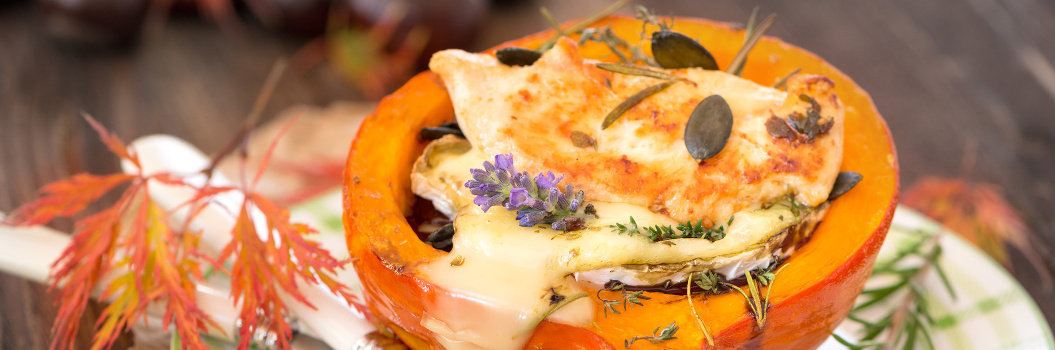 KI generiert: Gefüllter Kürbis mit geschmolzenem Käse, Kürbiskernen und Lavendel dekoriert.