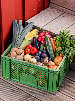 KI generiert: Eine grüne Kiste voller frischem Obst und Gemüse auf Holzboden.