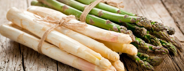 KI generiert: Bündel von weißem und grünem Spargel auf einem Holztisch.