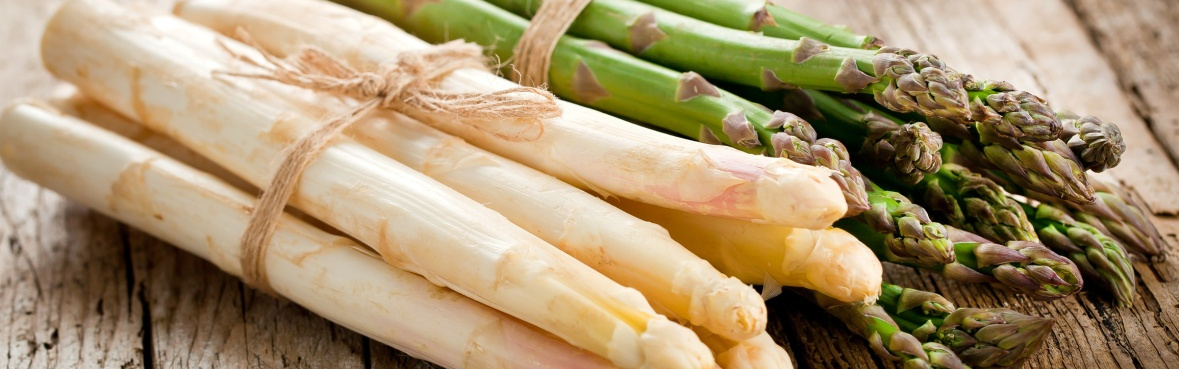 KI generiert: Weiße und grüne Spargelbündel auf einem Holztisch.