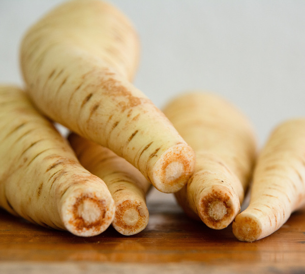 KI generiert: Nahaufnahme von mehreren Pastinaken auf einem Holztisch.