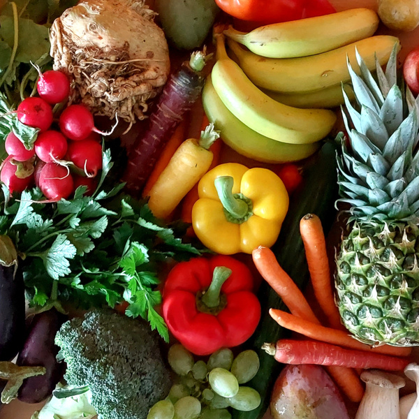 KI generiert: Verschiedene Früchte und Gemüse, inklusive Ananas, Paprika und Bananen, auf einem Tisch arrangiert.