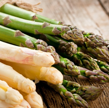 KI generiert: Weiße und grüne Spargelstangen liegen auf einem Holztisch.