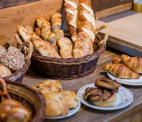 KI generiert: Korb mit verschiedenen Broten und Gebäck auf einem Holztisch.