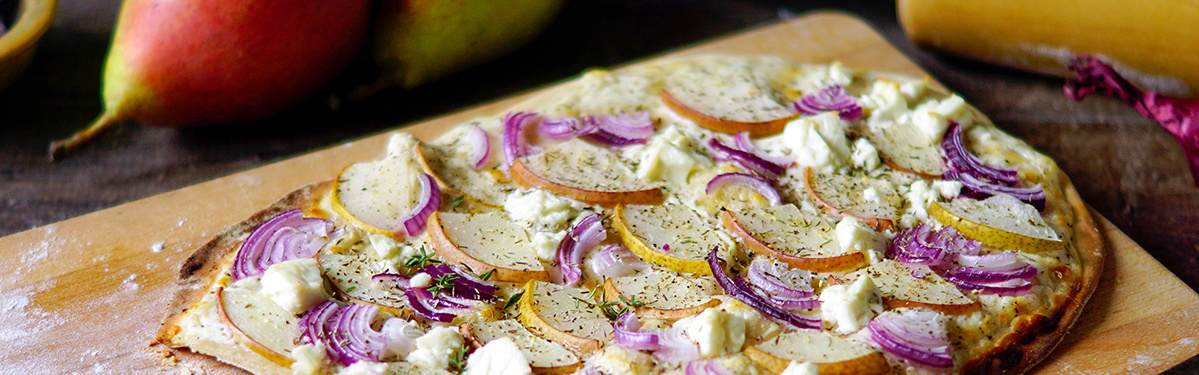 KI generiert: Flammkuchen mit Birnen, Zwiebeln und Käse auf Holzbrett.